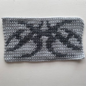 May include: A gray and black crocheted square with a geometric pattern.