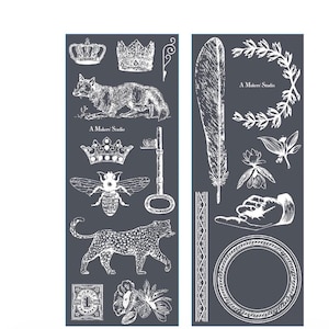 May include: Two dark gray sheets with white illustrations of crowns, a fox, a bee, a leopard, a key, a feather, a hand, and floral elements. The text "A Makers' Studio" appears on both sheets. Decorative design elements.