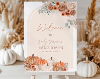 Op de afbeelding: Welkom bij Emily Johnson's Baby Shower bord met een aquarel bloemenontwerp en pompoenen. Het bord staat op een wit ezel en zegt "Welkom bij Emily Johnson's Baby Shower, 14 oktober 2024".