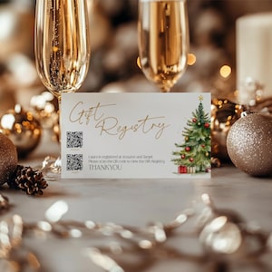 May include: A white card with gold lettering that says "Gift Registry". Two QR codes are on the card. The card is decorated with a watercolor painting of a Christmas tree with red ornaments. The text below the QR codes says "Laura is registered at Amazon and Target. Please scan the QR code to view the gift registry. THANK YOU!"