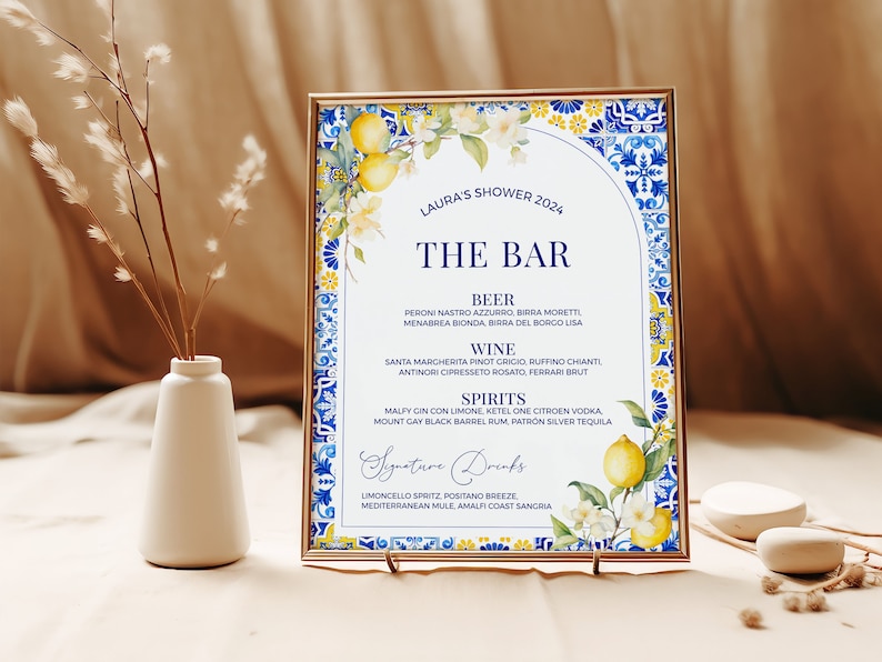 Op de afbeelding: Een afdrukbaar bord voor een bruidsdouche met een blauw en geel betegeld ontwerp. Het bord vermeldt de barmenu met bier-, wijn- en sterke drankopties. De tekst luidt "Laura's Shower 2024" en "The Bar".