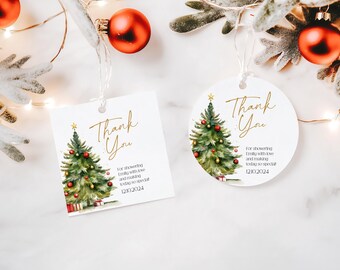 Op de afbeelding: Twee witte bedankkaartjes met een aquarel-illustratie van een kerstboom versierd met rode kerstballen en gouden lichtjes. De tekst op de kaartjes is "Bedankt" in gouden letters. De tekst onder de illustratie is "Voor het verwennen van Emily met liefde en het maken van deze speciale dag 12/10/2024".