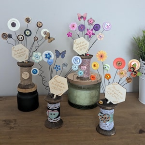 May include: Four decorative wooden spools with wire stems, buttons, and fabric flowers. Each spool has a sign that reads "Thank you for helping me GROW!"