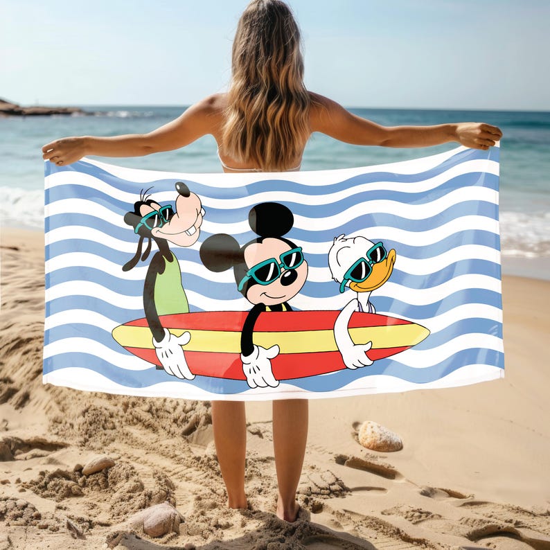 May include: A blue and white striped beach towel featuring Mickey Mouse, Goofy, and Donald Duck wearing sunglasses and riding a surfboard. The characters are depicted in a cartoon style.