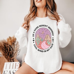 May include: White sweatshirt with a graphic print of a desert landscape with the text "On a dark desert highway, cool wind in my hair."