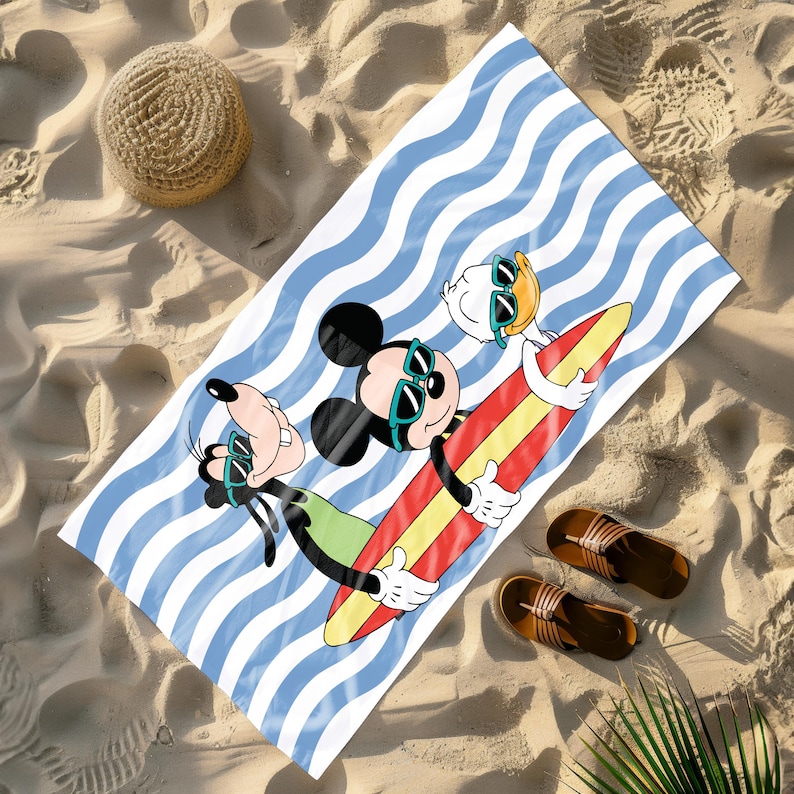 May include: A white beach towel with blue and white stripes. Mickey Mouse, Goofy, and Donald Duck are on the towel, riding a surfboard. They are all wearing sunglasses.