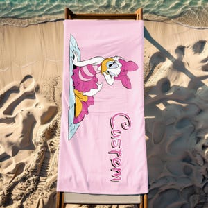 K&ouml;nnte beinhalten: Rosa Strandtuch mit einem Cartoon-Bild eines Entchens, das ein rosa Kleid tr&auml;gt, und dem Wort "Custom" in rosa Schrift.
