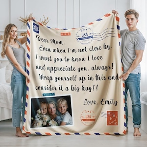 May include: Cream-colored blanket with a letter design, featuring a family photo and the text "Dear Mom, Even when I'm not close by...Love, Emily." The blanket has red and blue border stripes and USA stamps.
