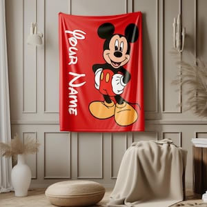 May include: A red blanket featuring a large graphic of Mickey Mouse in his classic pose. The blanket has the words "Your Name" in white script on the left side. Mickey is wearing red shorts, yellow shoes, and white gloves.