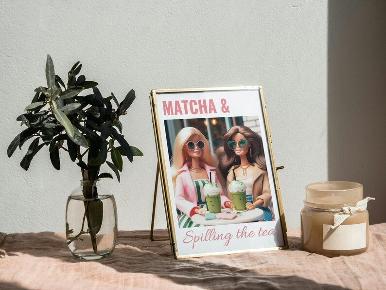 Puede incluir: Imagen enmarcada en oro con dos mu&ntilde;ecas sosteniendo bebidas verdes. La imagen dice "MATCHA & Spilling the tea".