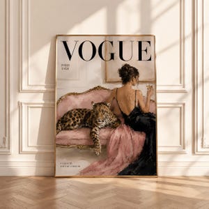 May include: A rectangular wall art print featuring a Vogue Paris 1958 magazine cover illustration. It depicts a person in a black dress sitting on a pink sofa next to a leopard, holding a glass. The text reads VOGUE, PARIS 1958, and LA BEAUTE EST UNE ATTITUDE.