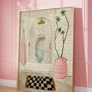 Könnte beinhalten: Gerahmter Kunstdruck, der eine Froschdusche in einem Badezimmer mit Ziegelmuster zeigt. Der Frosch trägt eine Duschhaube und hält einen Waschlappen. Eine rosa Vase mit grünen Pflanzen und ein schwarz-weiß karierter Teppich sind ebenfalls im Bild zu sehen.