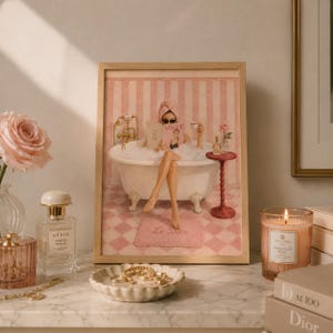 May include: A framed art print depicting a person in a clawfoot bathtub filled with bubbles, wearing a towel wrap and sunglasses while reading a magazine. The scene features pink striped walls, a checkered floor, and a small side table with a cup.