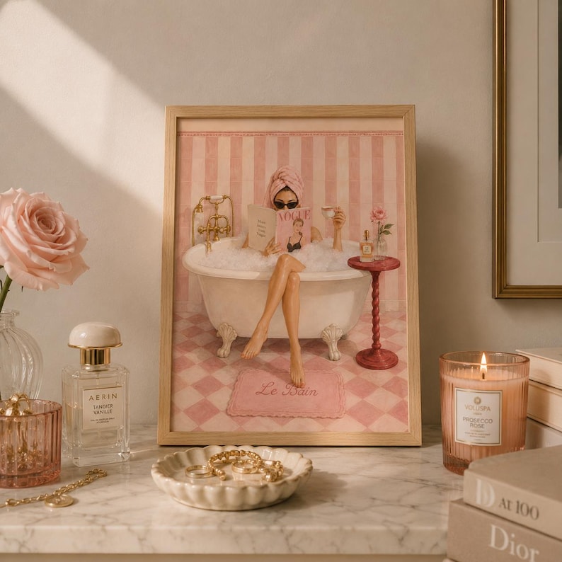 May include: A framed art print depicting a person in a clawfoot bathtub filled with bubbles, wearing a towel wrap and sunglasses while reading a magazine. The scene features pink striped walls, a checkered floor, and a small side table with a cup.