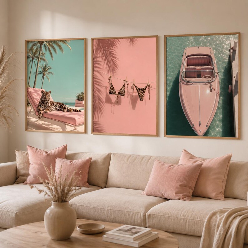 May include: A set of three framed wall art prints. The left print shows a leopard on a pink lounge chair under palm trees. The middle print features a leopard print bikini hanging on a line against a pink background. The right print depicts a pink boat.