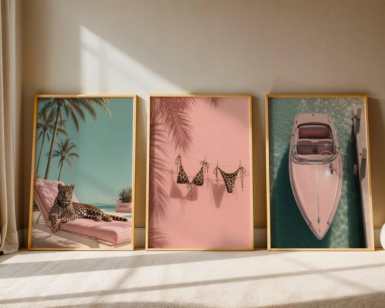May include: Three framed wall art prints featuring a leopard resting on a pink lounge chair under palm trees, a leopard print bikini hanging on a clothesline against a pink wall with palm shadows, and a pink boat docked in turquoise water.