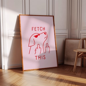 Könnte beinhalten: Ein gerahmter rosa Kunstdruck mit einer roten Illustration eines Hundes mit Sonnenbrille, der den Mittelfinger zeigt. Der Text "FETCH THIS" steht über und unter der Hundeillustration. Der Rahmen hat eine warme braune Farbe.