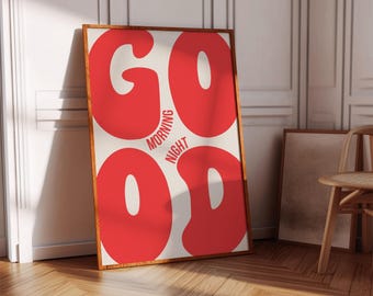 Op de afbeelding: Een ingelijste kunstprint met het woord "GOOD" in grote rode letters boven "MORNING NIGHT" en het woord "GOOD" in grote rode letters. De print heeft een lichtbeige achtergrond en een houten lijst. De print leunt tegen een witte muur.