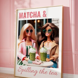 Puede incluir: Una impresi&oacute;n enmarcada con fondo rosa y marco dorado. La impresi&oacute;n presenta dos mu&ntilde;ecas Barbie con gafas de sol y sosteniendo bebidas de matcha verdes. El texto "MATCHA & Spilling the tea" est&aacute; impreso en rosa en la impresi&oacute;n.