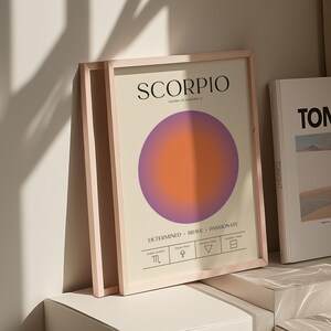 May include: Framed art print featuring the word "SCORPIO" in black text above a gradient circle in purple and orange. The print includes zodiac symbols and the words "Determined, Brave, Passionate."