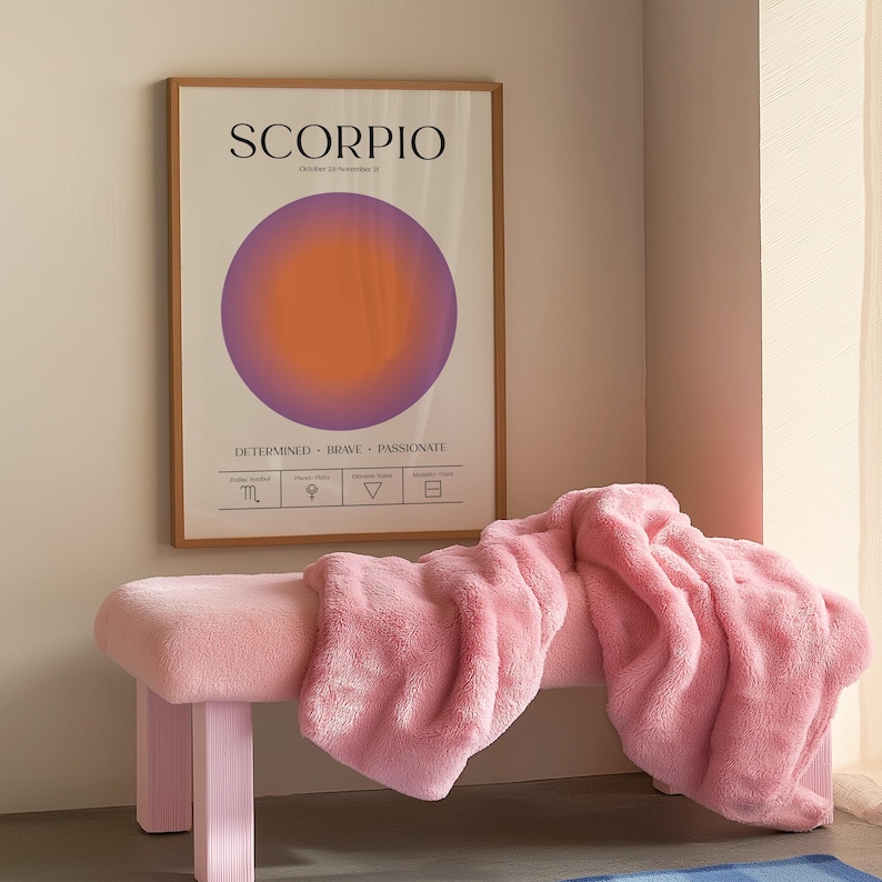 May include: A framed poster with the word "SCORPIO" and a purple and orange circular design. Below the poster is a pink bench with a pink fluffy blanket draped over it. The bench has a rectangular seat and four legs.