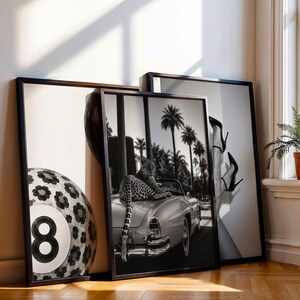 May include: Three framed black and white wall art prints. The left print shows a large number eight billiard ball with a floral pattern. The center print features a leopard resting on the back of a vintage convertible car with palm trees. The right print displays a pair of legs wearing high-heeled shoes.