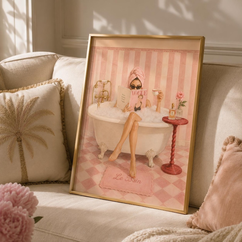 May include: A framed wall art print depicting a person in a clawfoot bathtub filled with bubbles, wearing a pink towel wrap and sunglasses, reading a magazine titled Vogue. The scene features pink striped walls, a checkered floor, and a pink rug with the text Le Bain.