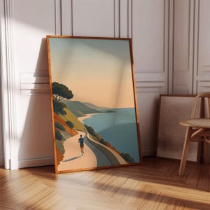 以下が含まれることがあります： 海岸沿いの道を走るランナーを描いた額入りのアートプリント。青、緑、オレンジの色使いで、木と丘が海を見下ろしています。木製の床と椅子のある部屋にプリントが飾られています。