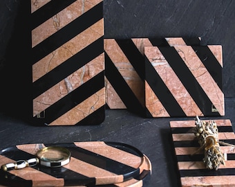 May include: Set of four black and pink striped marble serving trays. The trays are in different sizes and shapes, including a rectangular tray, a square tray, and an oval tray. The trays are made of natural marble and have a unique, hand-crafted look.