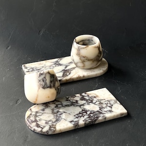 May include: Two marble trays with a white and grey marbled pattern. Each tray has a matching marble cup with a white and grey marbled pattern.