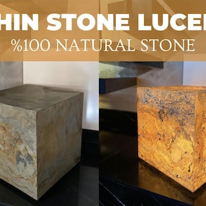Puede incluir: Un cubo hecho de THIN STONE LUCENT %100 NATURAL STONE. El lado izquierdo muestra el cubo en un estado neutro con tonos grises y tierra, mientras que el lado derecho muestra el mismo cubo iluminado desde dentro, revelando un cálido brillo naranja.