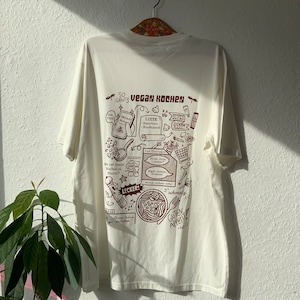 Weißes oversized T-Shirt mit braunem Backprint. Vegan Kochen im retro Cartoon style, unisex