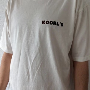 Weißes oversized T-Shirt mit braunem Logo vorne. Vegan Kochen im retro Cartoon style, unisex, nachhaltig