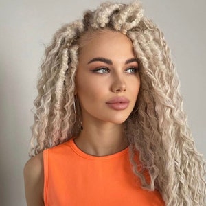May include: A woman with long, blonde, curly hair wearing a bright orange sleeveless top.