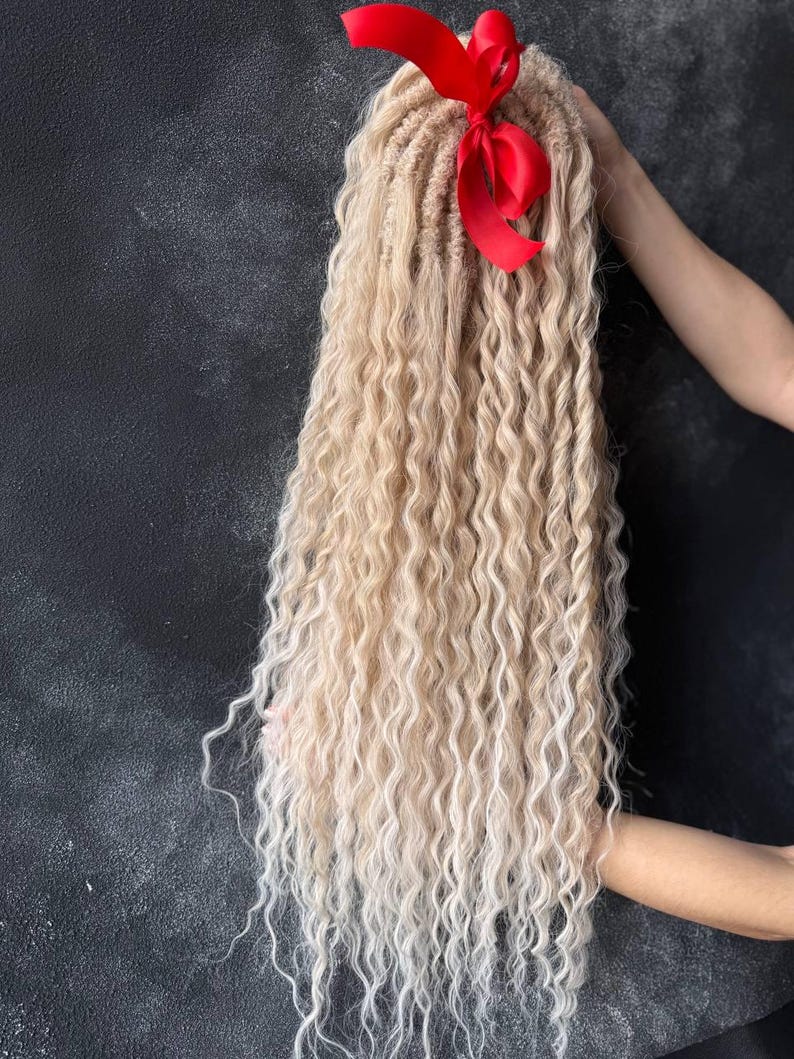 May include: Long blonde ombre synthetic dreadlocks with a red ribbon tied at the top.