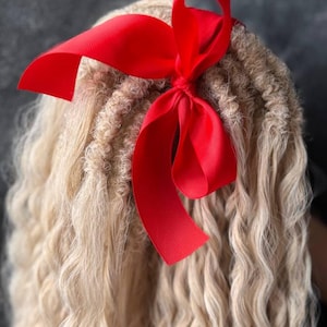 May include: A close-up of a blonde hair extension with a red ribbon tied in a bow. The hair is in a wavy style. The text "color: 16a/56c" is visible in the image.