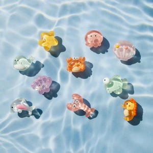 Peut inclure: Un ensemble de neuf jouets de bain colorés en forme de créatures marines, comprenant une étoile de mer, un crabe, une méduse, un dauphin, un hippocampe et un coquillage. Les jouets sont en plastique souple et flexible et sont parfaits pour s'amuser dans le bain.