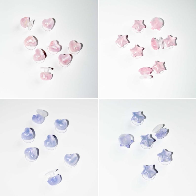 Op de afbeelding: Een verzameling hart- en stervormige oorstekers in roze en paarse tinten. De oorbellen zijn in groepen gerangschikt op een wit oppervlak. De oorbellen hebben een doorschijnend uiterlijk.