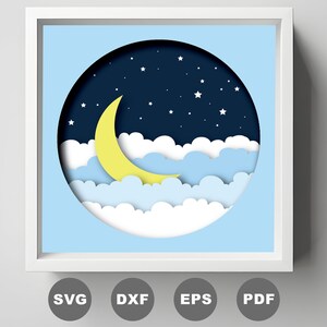 Pode incluir: Um design digital de artesanato em papel com uma lua crescente e estrelas em um céu noturno azul com nuvens brancas. O design é em forma de círculo e é perfeito para criar um projeto de artesanato em papel em camadas.