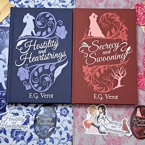 May include: Two hardcover books, "Hostility and Heartstrings" and "Secrecy and Swooning", with decorative floral and silhouette designs. Accompanying stickers, bookmarks, and crocheted hearts in blue and pink hues complete the romantic theme.