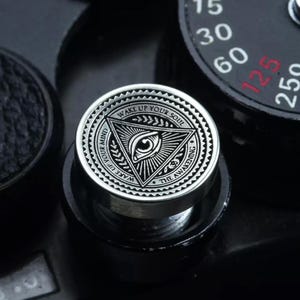 May include: A silver-toned metal camera knob with an all-seeing eye design and the text "Wake Up Your Mind, Wake Up Your Soul, The Awakening".