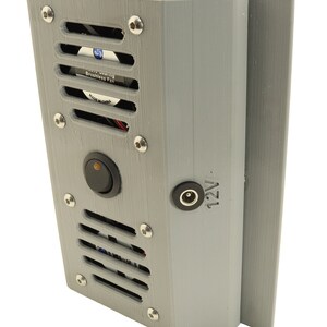 May include: A grey 3D printed box with a black switch, a power cord, and a small fan with a black grill. The fan has a white label that reads "Sleeve Bearing Brushless Fan Made in China". The box has a label that reads "12V".