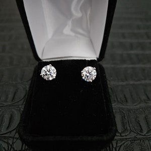 May include: A pair of round, clear diamond earrings in a black velvet jewelry box.