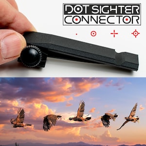 May include: A black plastic device called "DOT SIGHTER CONNECTOR" with a red dot in the center of the word "CONNECTOR". The device has a knob on the left side and a slot on the right side. The device is being held by a hand.
