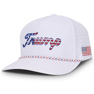 May include: White baseball cap with a red, white, and blue American flag design. The word "Trump" is embroidered on the front of the cap in a cursive font with red, white, and blue stripes.