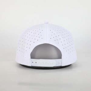 May include: White baseball cap with a perforated design for breathability. The cap features a curved brim and an adjustable strap at the back for a custom fit. The hat is a classic accessory for sun protection and casual wear.