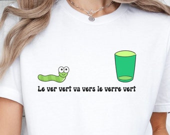 May include: White t-shirt with a green worm and a green glass on it. The text on the shirt reads "Le ver vert va vers le verre vert".