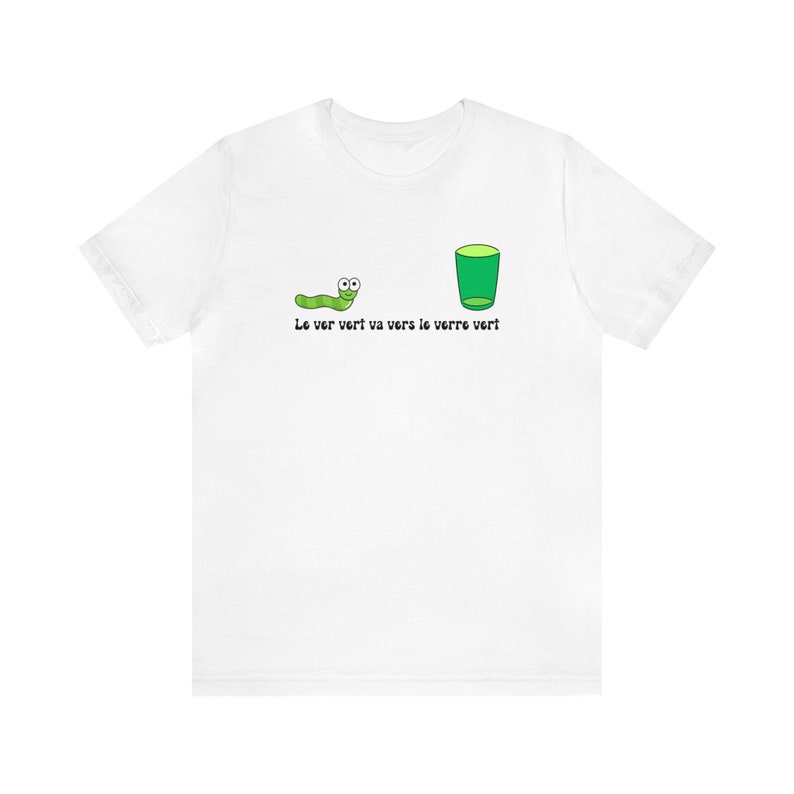以下が含まれることがあります： 緑の虫と緑のグラスが描かれた白いTシャツ。画像の下に「Le ver vert va vers le verre vert」というテキストが印刷されています。