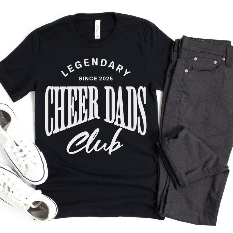 May include: Black t-shirt with white text that reads "Legendary Since 2025 Cheer Dads Club".