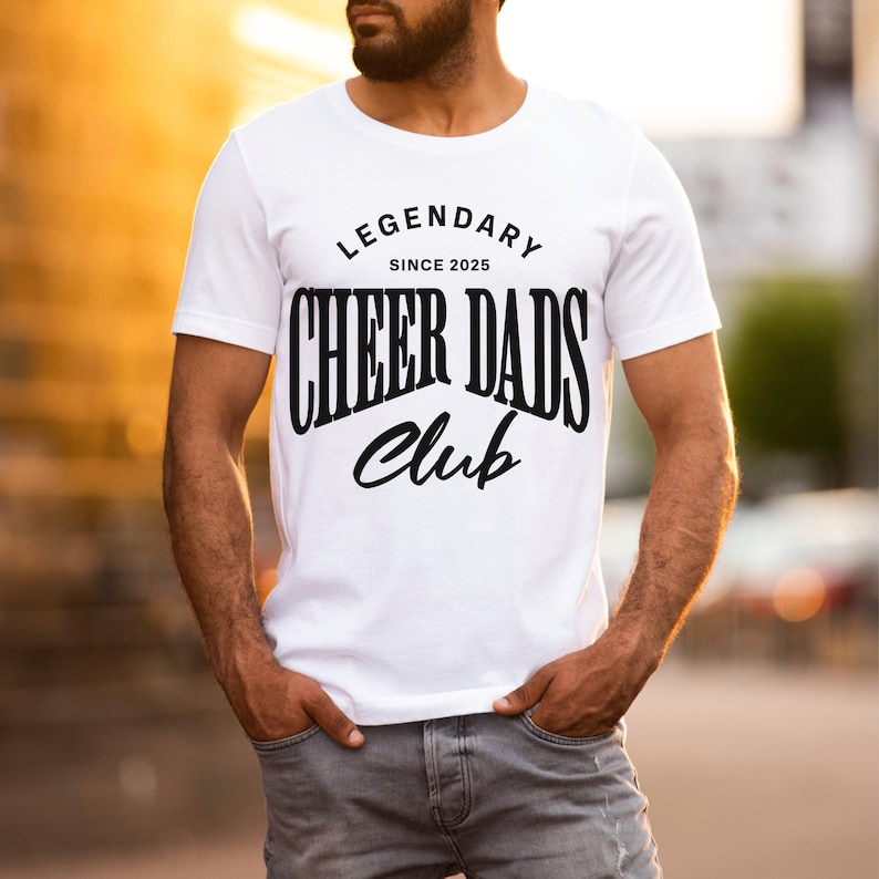 May include: White t-shirt with black text that reads "Legendary Since 2025 Cheer Dads Club".